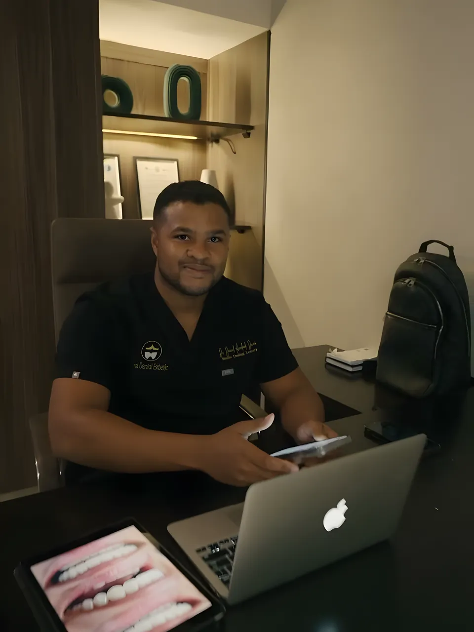 Dr. Daniel at his desk with a smile design on screen